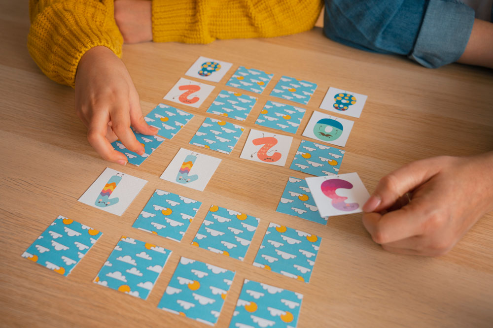 Kind spielt ein Lernspiel mit Karten am Tisch