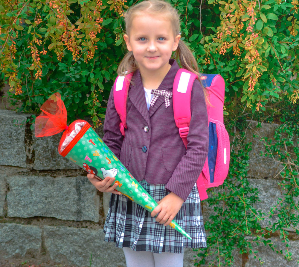 Kind hält stolz seine Schultüte am ersten Schultag