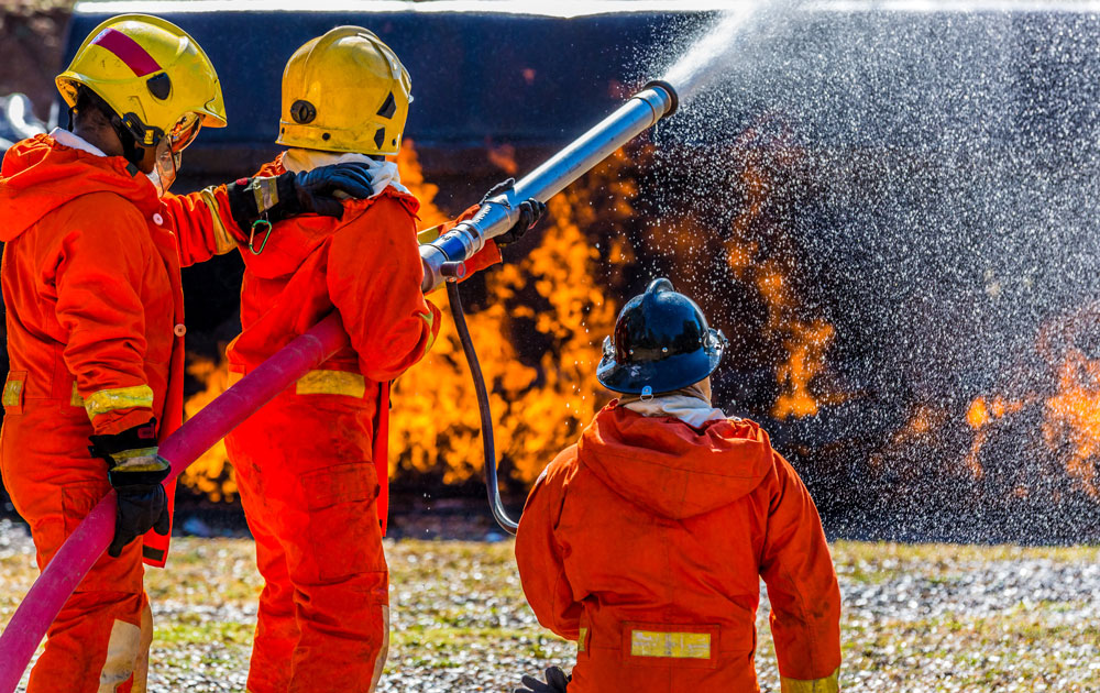 Kinder in der Feuerwehr bei einer spielerischen Übung mit Wasser und Schläuchen