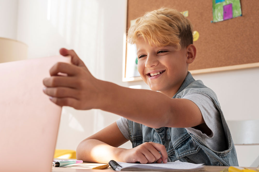 Junge lächelt am Schreibtisch vor dem Laptop