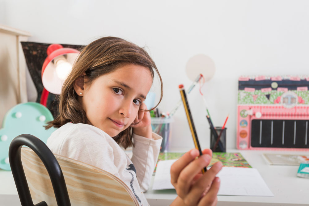 Mädchen zeigt stolz einen Bleistift in die Kamera